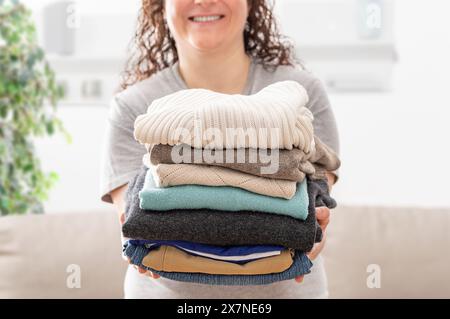 Closeup shot of a young woman holding a pile of folded laundry at home Stock Photo