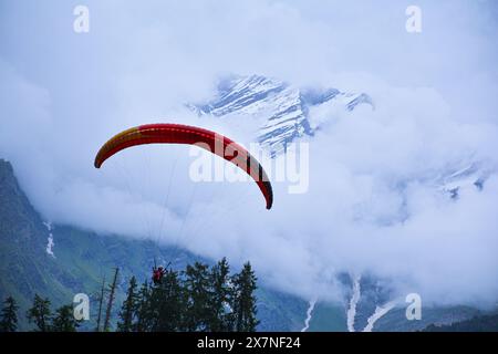 The beautiful photo depicts the extreme sport of paragliding with the beautiful and snowcapped Himalayan mountain range in the backdrop. Stock Photo