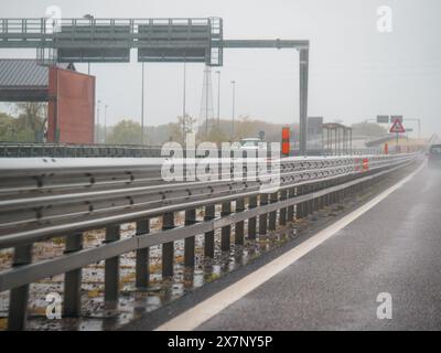 Piacenza, Italy -April 22nd 2024 A highway scene under an overcast sky featuring cars and trucks with road signs and an overpass, rainy day on Motorwa Stock Photo