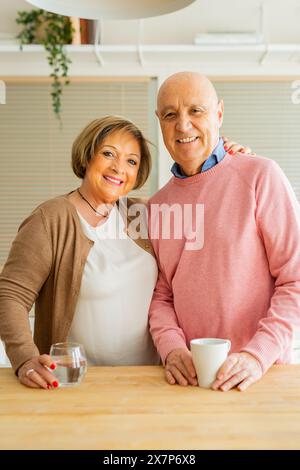 Portrait of a smiling senior couple standing together in a kitchen. Stock Photo