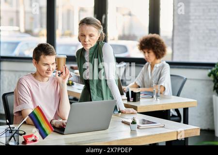 Attentive diverse businesswomen working together on project in office, pride flag. Stock Photo