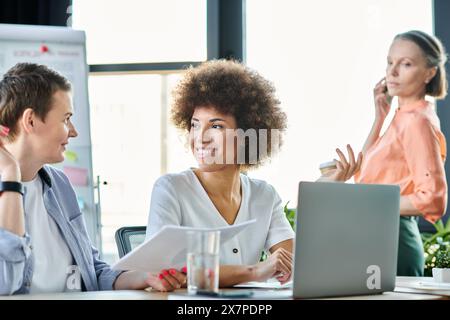 A group of hard-working, diverse businesswomen engaged in a lively discussion around a table in a coworking space. Stock Photo