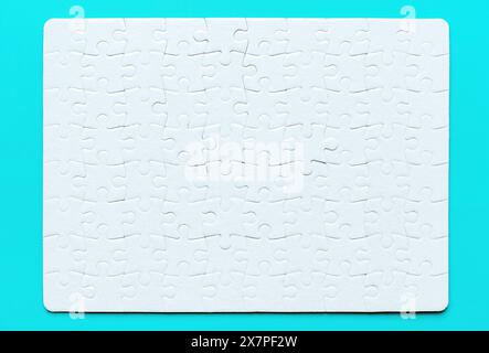 Close-up of a blank rectangular jigsaw puzzle isolated on light blue background. Stock Photo
