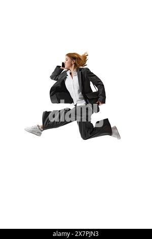 Businesswoman in formal attire having call in mid-air against white studio background. Flexibility and grace in business. Stock Photo