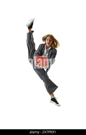 Dynamic Professionalism. Businesswoman performing high kick in motion and holding folder against white studio background. Stock Photo