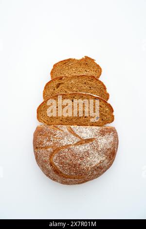 A whole loaf of sourdough rye bread and slices arranged in a row against a white background, showcasing the texture and crust. Stock Photo