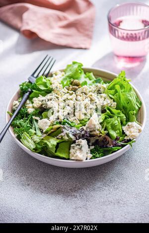 Fresh and healthy herb mix salad with lettuce, green onion, parsley, tarragon, blue brie cheese, and fermented capers, drizzled with olive oil, served Stock Photo