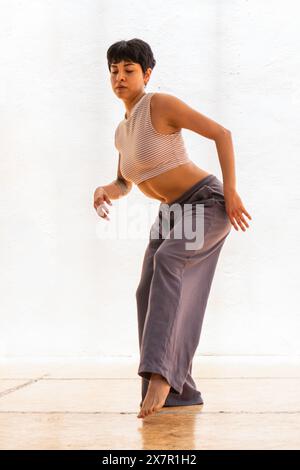 A focused young woman engages in a mindful holistic dance, expressing her spirituality through movement Stock Photo