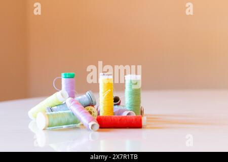 An array of multicolored thread spools and buttons scattered across a designer's workspace, reflecting creativity and the sewing process Stock Photo