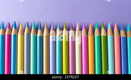Colorful wooden crayons on a purple paper background Stock Photo