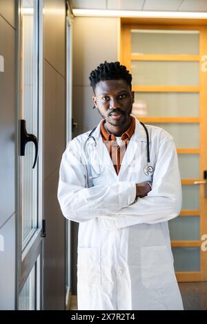 A professional male doctor, standing confidently in a clinic, poses for a discussion on hypoglycemia He's prepared to educate on symptoms, treatments, Stock Photo