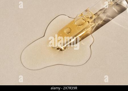 A close-up image showcasing the detailed texture of golden serum and white cream smears spread on a textured paper background, demonstrating cosmetic Stock Photo