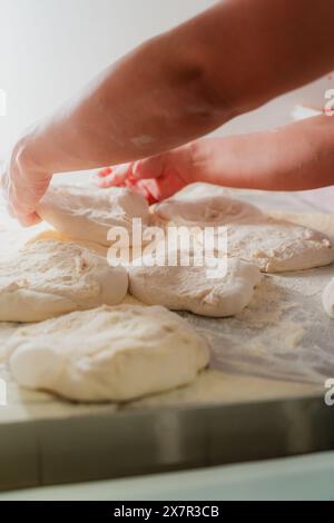 An anonymous chef prepares fresh pizza dough, hands working delicately on the flour-coated surface Stock Photo