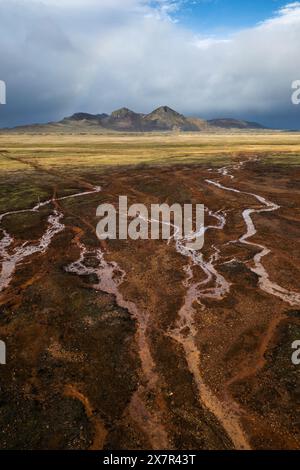 Stark beauty unfolds in this dramatic shot of the highland landscapes, with winding streams cutting through the rich, peaty soil under a stormy sky Stock Photo