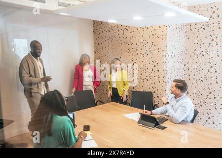 A multicultural group of professionals engaging in a brainstorming session at a stylish coworking office, with a focus on teamwork and communication Stock Photo