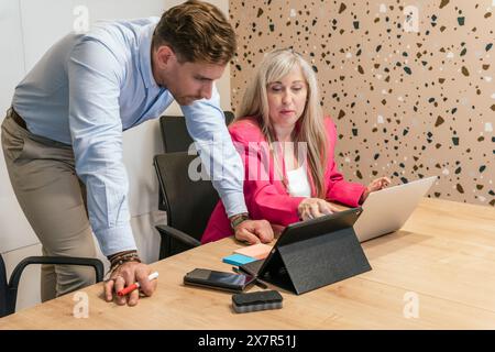 Two professionals collaborating in a well-designed coworking space, focused on a digital task Stock Photo
