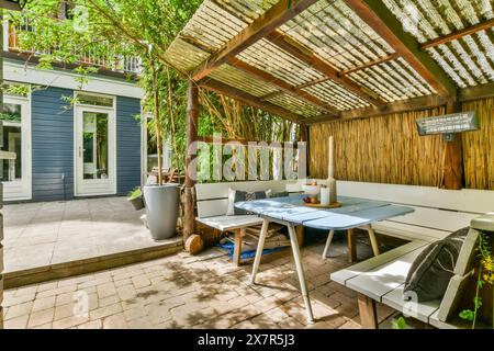 An inviting city backyard patio featuring a wooden pergola, lush greenery, a comfortable outdoor dining set, and a peaceful ambiance Stock Photo