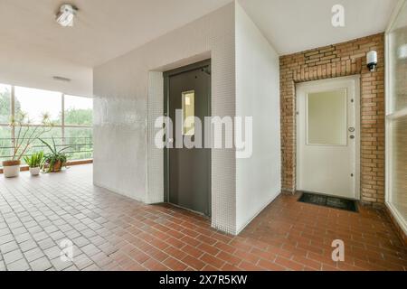 A well-lit, spacious balcony featuring terracotta tiles, potted plants, brick walls, and two contrasting doors one white and one dark. Stock Photo