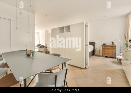 Bright and spacious minimalist kitchen with dining table set and open living space in a contemporary home. Stock Photo