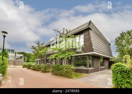 A contemporary suburban home with large windows, lush greenery, and a clear blue sky, showcasing comfortable living outside the bustling Madrid city Stock Photo