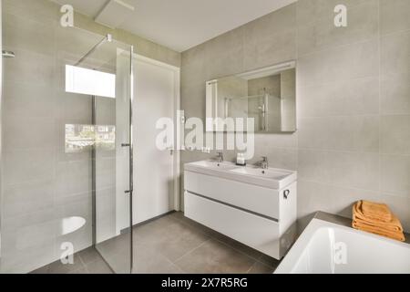 This image showcases a sleek, modern bathroom featuring a walk-in shower, floating vanity, and ample natural lighting, located in Madrid city The desi Stock Photo