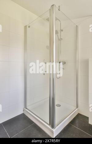 Modern glass shower cubicle in a clean, white tiled bathroom. Stock Photo