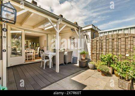 This inviting image showcases a beautifully arranged backyard patio in Schaarweg, Amsterdam, featuring a relaxing seating area, lush potted plants, an Stock Photo