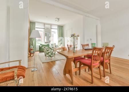 A well-lit, spacious living room featuring wooden floors, a large dining table, and stylish furnishings set in a charming Amsterdam residence on Schap Stock Photo