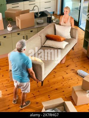 Overhead Shot Of Mature Couple Carrying Sofa Moving Furniture Into New Home On Moving Day Stock Photo