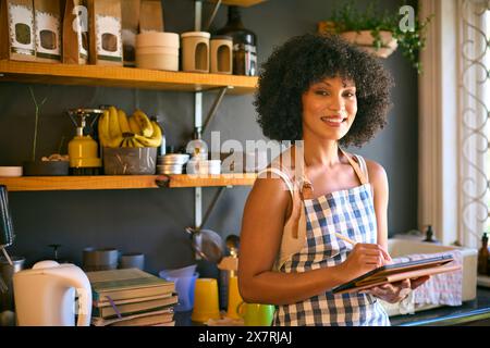 Portrait Of Woman Working In Sustainable Plastic Free Grocery Store Using Digital Tablet Stock Photo