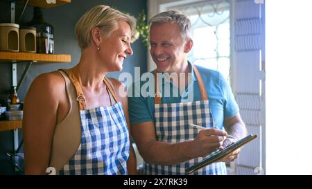 Mature Couple Working In Sustainable Plastic Free Grocery Store Checking Stock With Digital Tablet Stock Photo