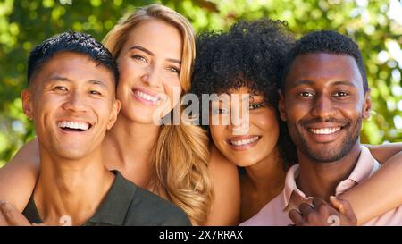 Portrait Of Multi-Racial Couple With Friends Hugging Outdoors In Countryside In Group Together Stock Photo