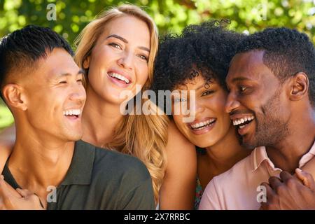 Portrait Of Multi-Racial Couple With Friends Hugging Outdoors In Countryside In Group Together Stock Photo