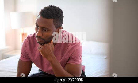 Unhappy Or Depressed Man Sitting On Bed At Home Stock Photo