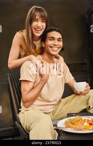 An interracial couple enjoying a romantic lunch together in a camper van. Stock Photo