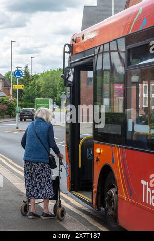 Elderly woman with a walker boarding a bus in town, England, UK Stock Photo