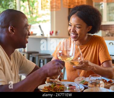 Smiling Couple Enjoying Meal At Home Together Doing Cheers With Glasses Of Wine Stock Photo