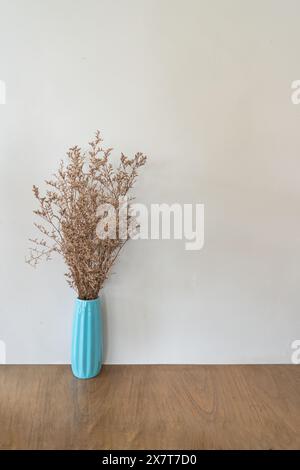 Dried flower in turquoise vase on wooden table over beige wall background Stock Photo