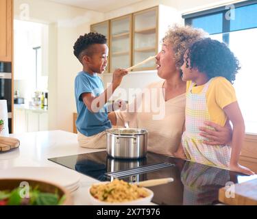 Grandchildren Helping Grandmother Prepare Meal In Kitchen At Home Having Messy Fun Together Stock Photo