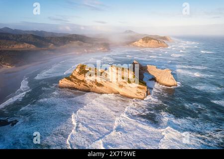 Aerial view of Picturesque sunrise shining over Wharariki beach and archway islands on Tasman sea at West of cape farewell, New Zealand Stock Photo