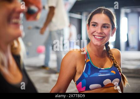 Close Up Of Two Women Taking A Break And Talking By Climbing Wall In Indoor Activity Centre Stock Photo