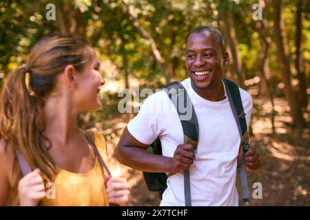 Young Active Couple Wearing Backpacks Hiking Along Trail Through Countryside Stock Photo