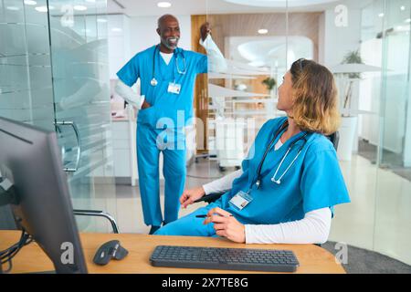 Male And Female Doctors Wearing Scrubs Having Informal Meeting In Hospital Office Stock Photo