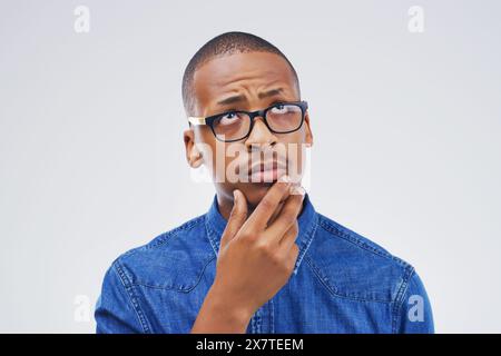 Thinking, glasses and man in studio with idea for choice, decision and options on white background. Question, wondering and face of isolated person in Stock Photo