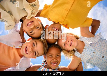 Group Of Multi-Cultural Children Friends Linking Arms Looking Down Into Camera Stock Photo