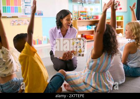 Class Of Primary Or Elementary School Students Raising Hands To Answer Question In Classroom Stock Photo