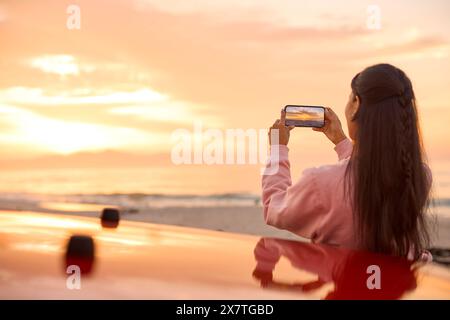 Close Up Of Young Woman Taking Photo Or Video Of Sunrise At Beach On Mobile Phone Stock Photo