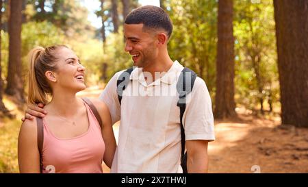 Portrait Of Couple Wearing Backpacks Hiking Along Trail Through Countryside Stock Photo