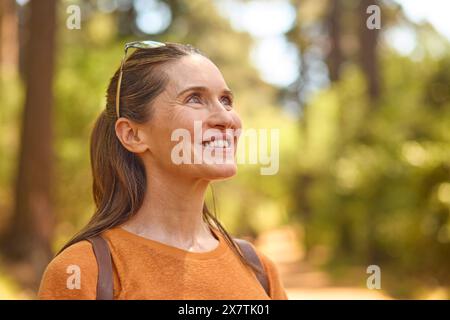 Smiling Senior Woman Relaxing In Nature Hiking Along Trail In Countryside Stock Photo