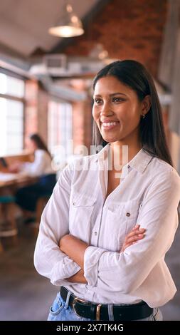 Portrait Of Smiling Young Businesswoman Working In Modern Open Plan Office Stock Photo